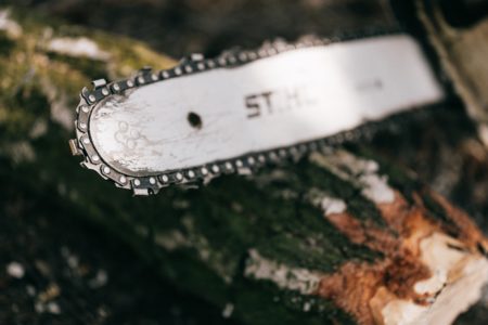 A well-used standard chainsaw resting on a log.